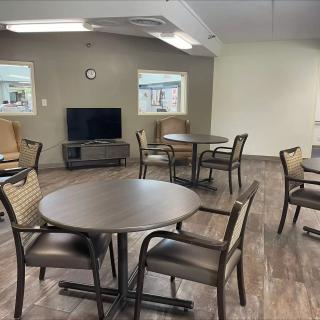 A community room with circular tables and chairs arranged around a television set.
