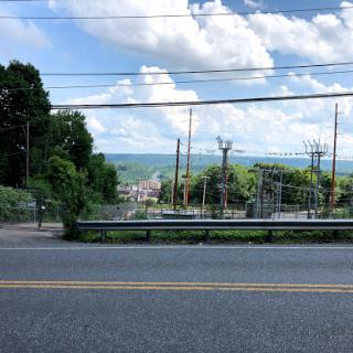 A scenic view showcasing a road lined with greenery under a cloudy sky.