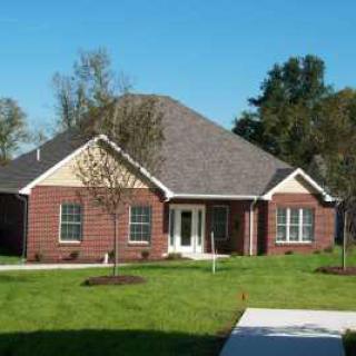 A suburban brick house with a well-maintained lawn and clear blue sky.
