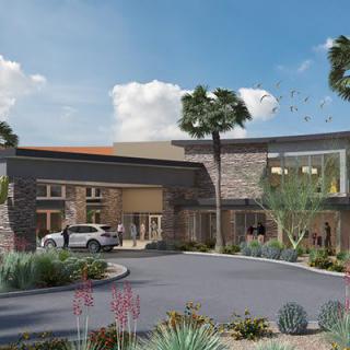 A modern building entrance surrounded by desert landscaping and palm trees.