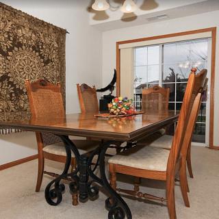 A cozy dining room featuring a wooden table with chairs, a decorative tapestry on the wall, and large sliding glass doors.