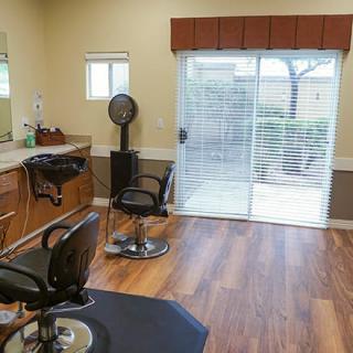 A modern hair salon with barber chairs, mirrors, and a hairdryer in a bright room with wooden flooring.