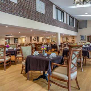 A spacious and elegantly decorated dining area with neatly arranged tables and chairs under a high ceiling.