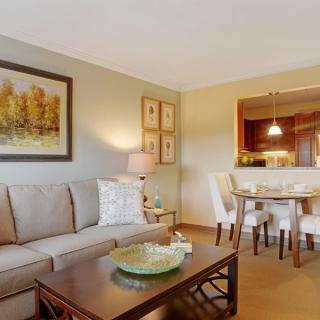 A cozy living room with a sofa, coffee table, and adjoining dining area.