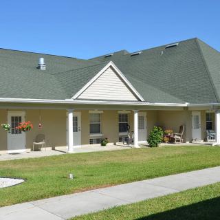 A single-story house with a green roof and a well-maintained front lawn.