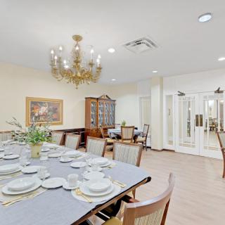 A formal dining room with a large table set for a meal, featuring a chandelier and elegant decor.