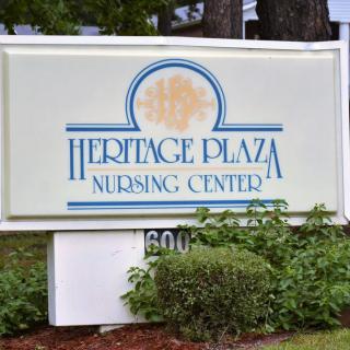 Sign for Heritage Plaza Nursing Center surrounded by greenery.