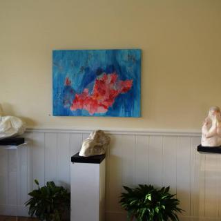 An art gallery display featuring a colorful abstract painting and several sculptures on pedestals.