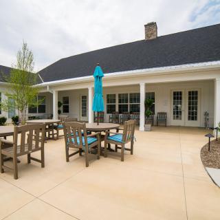 A spacious patio with tables, chairs, and an umbrella outside a building.