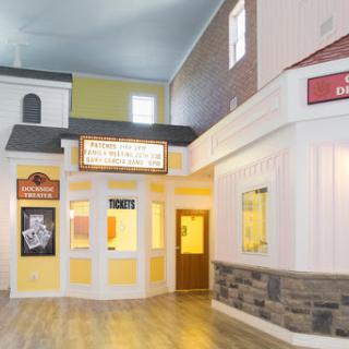 A vibrant interior space resembling a shopping center with a mix of architectural styles and theater signage.