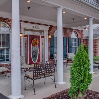 A welcoming porch with columns, outdoor seating, and a brick exterior.