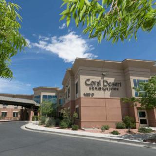 A medical facility under a partly cloudy sky, surrounded by trees.