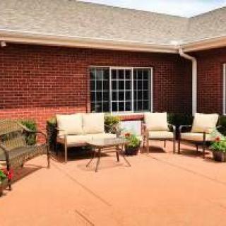 Outdoor patio with seating and plants by a brick building.