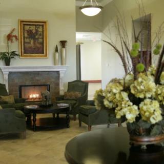 A cozy living room with a fireplace, comfortable seating, and decorative flowers.