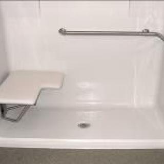 An accessible shower with a folding seat and safety bar.