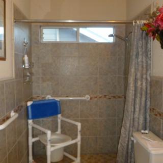 An accessible bathroom with a shower chair and safety rails.