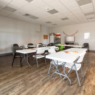 A spacious meeting room equipped with tables and chairs, ready for a group gathering.