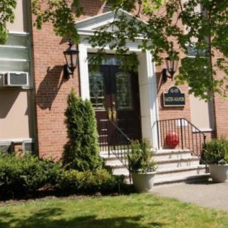 A brick building entrance surrounded by greenery with steps leading up to the door.
