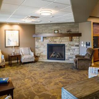 A cozy living room interior featuring a stone fireplace, comfortable armchairs, and warm decor.