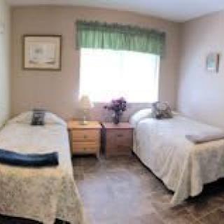 A cozy bedroom with two neatly arranged single beds and a window in the center letting in natural light.