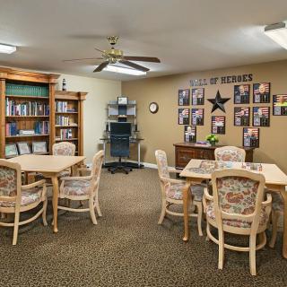 A cozy library reading area with tables, chairs, and bookshelves.