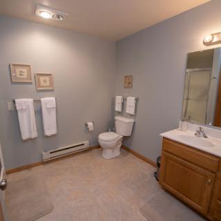 A spacious and well-lit bathroom featuring a toilet, sink, and neatly arranged towels.