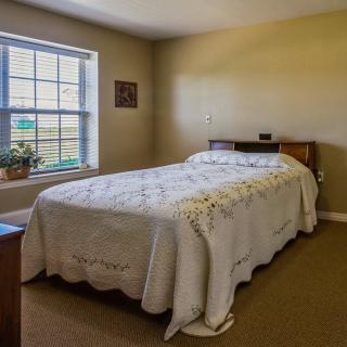 A cozy bedroom with a neatly made bed and a window letting in natural light.