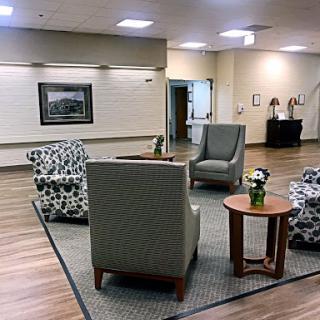 A cozy seating area in a modern lobby, featuring patterned chairs and a small table with flowers.