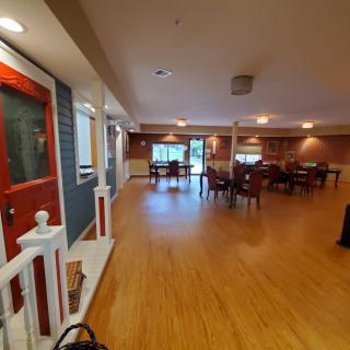 A spacious interior featuring a dining area with wooden floors and a distinctive red door.