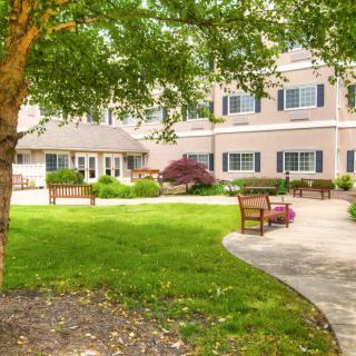 A tranquil garden with benches and a pathway leading to a building.