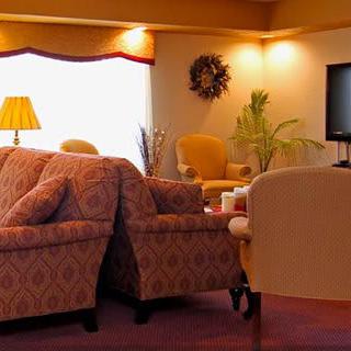 Cozy living room with sofas, chairs, a lamp, and a TV.
