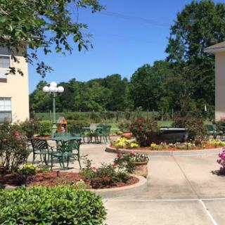 A beautifully landscaped courtyard with seating areas surrounded by colorful flowers on a sunny day.