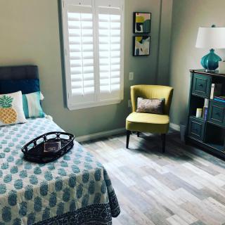 A cozy bedroom with a patterned bedspread, yellow chair, and stylish decor.