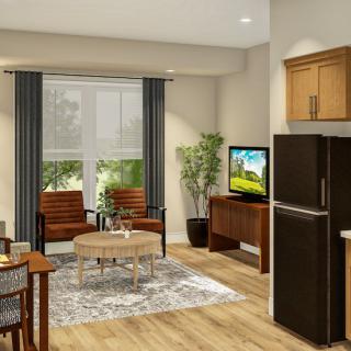 A modern living room with wooden flooring, featuring a television, chairs, and a small dining table.