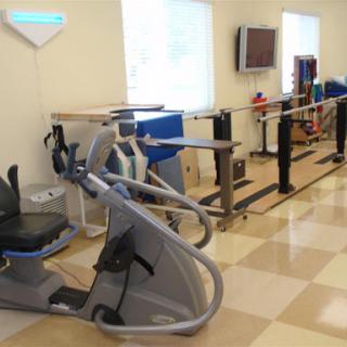 A well-equipped rehabilitation and exercise room featuring various fitness machines and therapy bars.