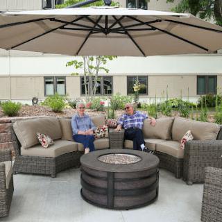 Two people enjoying a cozy outdoor seating area under a large umbrella.