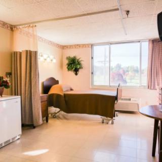 A well-lit hospital room with a bed, curtains, and a large window.