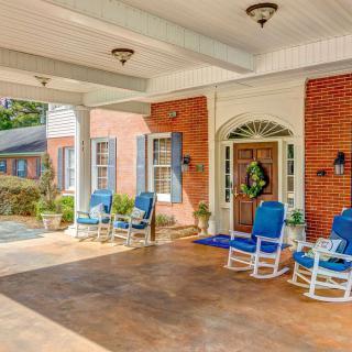 A welcoming porch with blue-cushioned rocking chairs and a decorative wreath on the door.