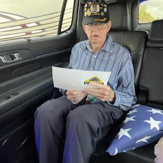 An elderly veteran reading a document while seated in a car.