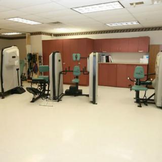 A gym with various exercise machines arranged in a spacious indoor setting.