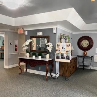 A well-decorated lobby area featuring a mirror, plants, and a large wall clock.