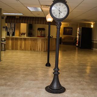 A vintage-style standing clock and lamp in the lobby of a reception area.