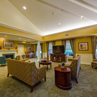 A spacious, elegantly decorated living room with comfortable seating and a large television.