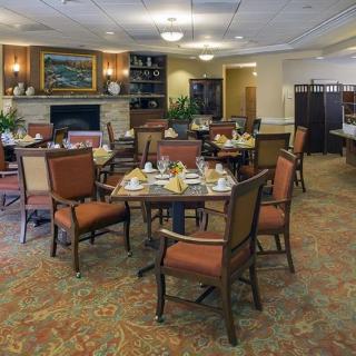 A cozy dining room with neatly arranged tables and chairs, featuring warm lighting and elegant decor.