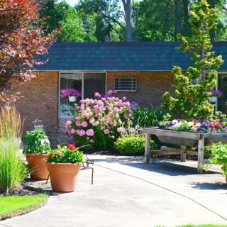 A vibrant garden with potted plants and flowers surrounding a cozy patio area.