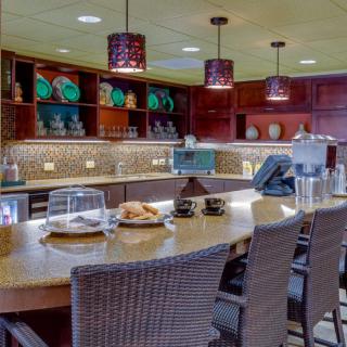 A well-appointed kitchen interior with a central counter, seating, and decorative shelving.
