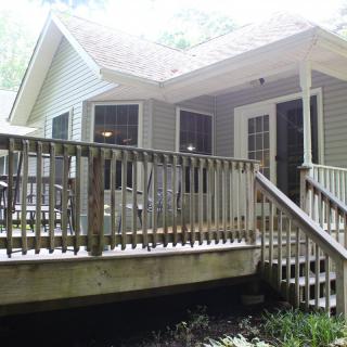 A cozy house with a wooden deck and stairs.