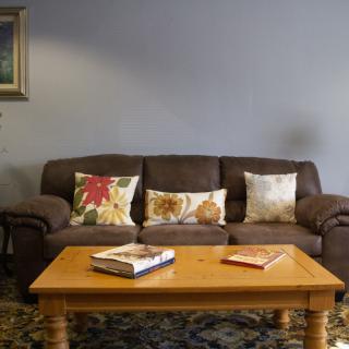 A cozy living room setup with a brown sofa adorned with patterned cushions and a wooden coffee table holding books.