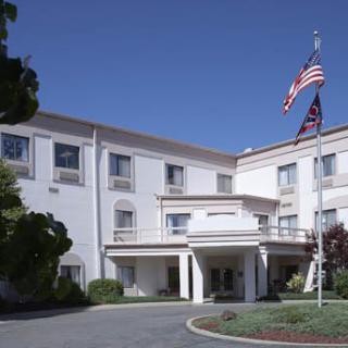 A building with a flagpole displaying American flags in front of an entrance.