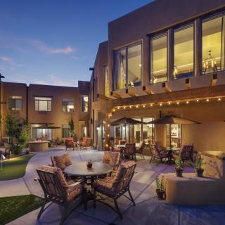 A cozy outdoor patio with comfortable seating and warm lighting in the evening.